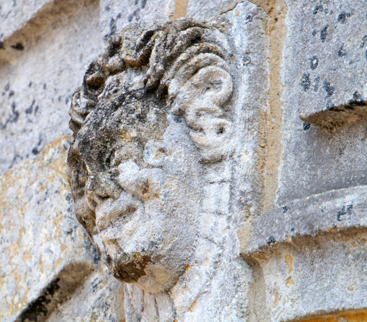 Faciès grimaçant au dessus du portail de l'église. - Orliac