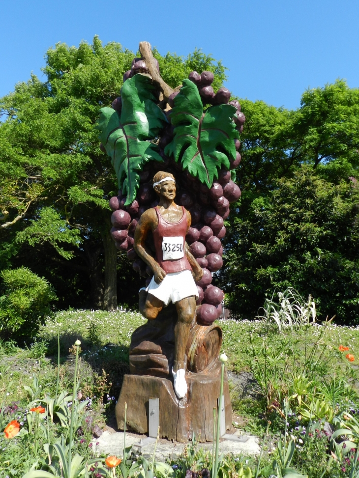 Le marathonien statue en bois peinte.  Le Marathon du Médoc ,créée en 1985, se tient tous les ans au mois de septembre à travers les vignobles du Médoc. Il est considéré comme « le Marathon le plus long du Monde ». - Pauillac