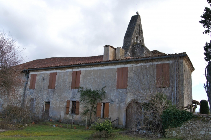 L'église Saint-Jean-Baptiste se dissimule sous une vaste toiture qui recouvre à la fois les parties nord et le presbytère accolé à son flanc. - Escalans