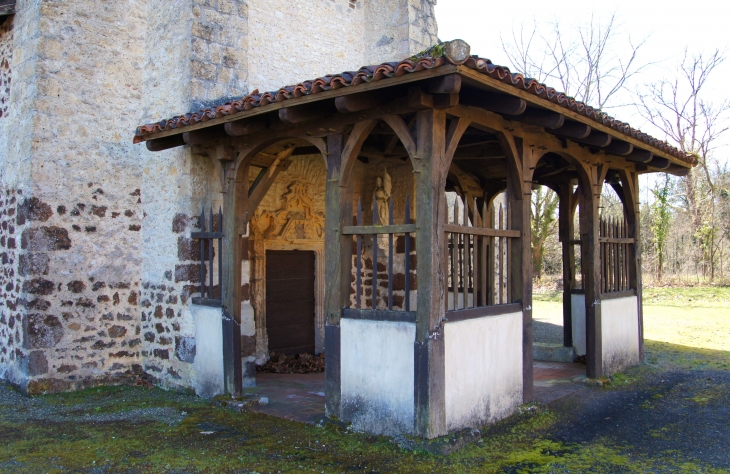 En avant de la façade occidentale qui forme clocher-mur, un porche grâcieux fait de bois et de maçonnerie abrite un portail du XVe ou du XVIe siècle, qui constitue l'élément le plus original de l'ensemble (photo 2013). - Lubbon