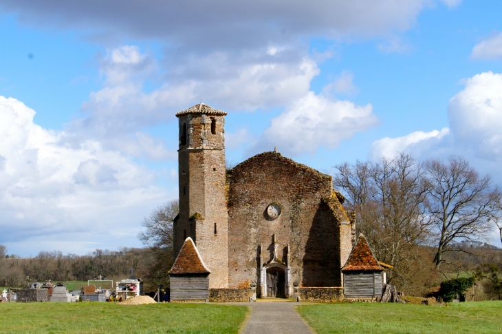 L'église Saint-André de Bouau dresse son imposante façade de briques à l'extrémité d'une allée . De part et d'autre du portail du cimetière qui l'entoure, deux petits bâtiments carrés, faits de torchis et de pans de bois, semblent veiller  - Parleboscq