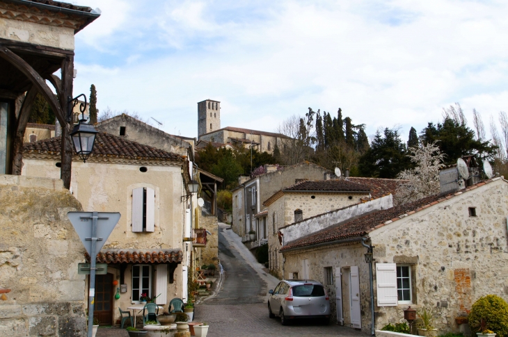 Vue sur l'église, place de la fontaine. - Poudenas