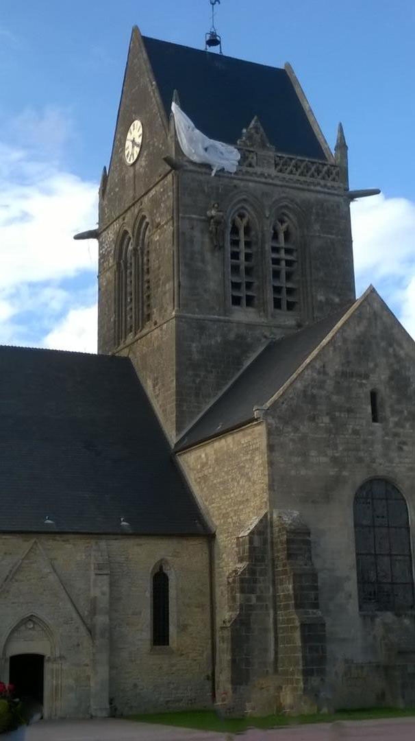 Le parachute sur le clocher. Photo de Jean-Paul Sculfort. Le 1er Janvier 2016 les communes Beuzeville-au-Plain, Chef-du-Pont, Écoquenéauville, Foucarville et Sainte-Mère-Église  ont fusionné  pour former la nouvelle commune  Sainte Mère Eglise.