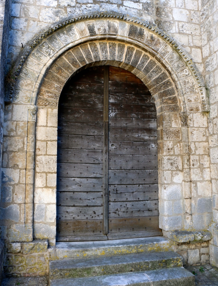 Eglise saint Marcel : le portail roman sur la façade : il comprend deux arcs plein cintre surmontés d'une archivolte en pointes de diamant. La 2ème voussure représente vraisemblablement les signes du zodiaque. - Saint-Marcel