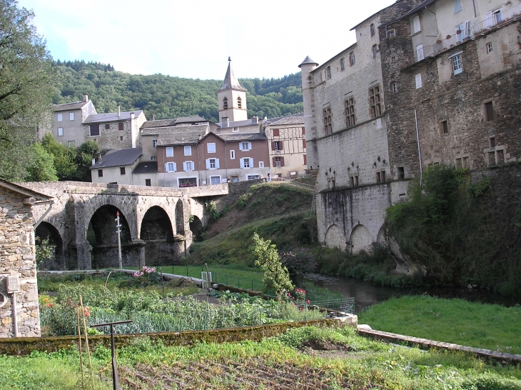 Le pont qui traverse le Gijou, le clocher de l'église, la façade du château restaurée, les jardins. - Lacaze