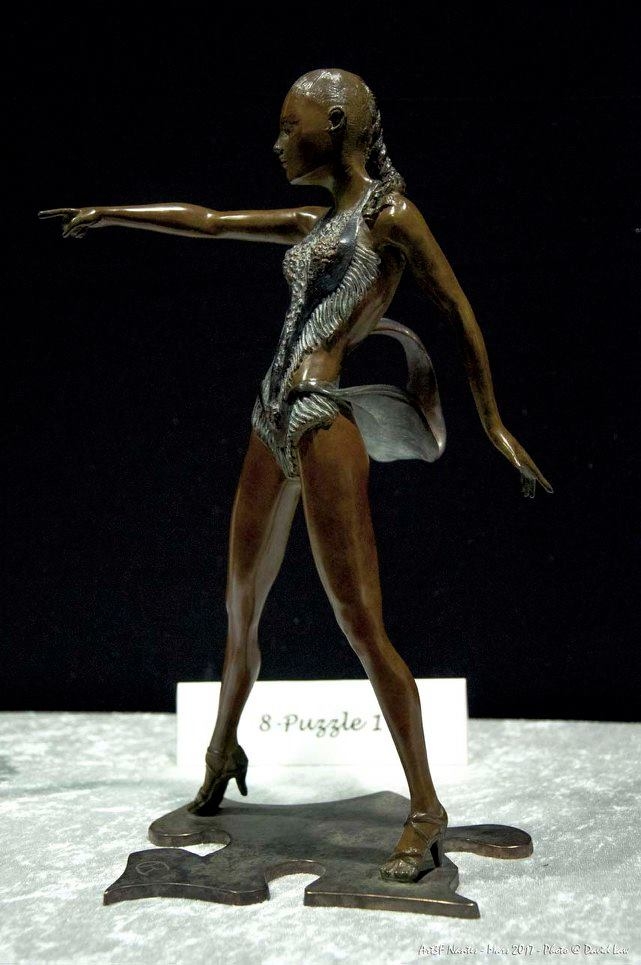 Puzzle Bronze 1/8 A la fin d’un Jive, la danseuse en habit de compétition, désigne son partenaire pour un hommage devant le public, sur une pièce de puzzle.  - Cogners