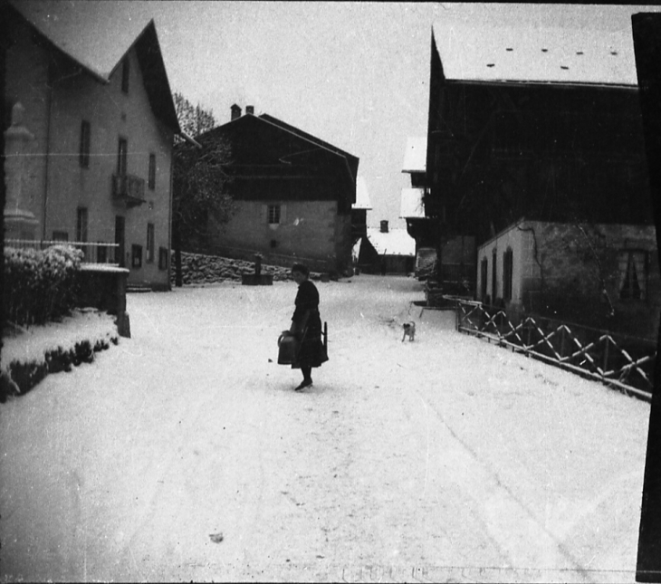 Rue principale avec une femme et 2 arrosoirs - Morillon